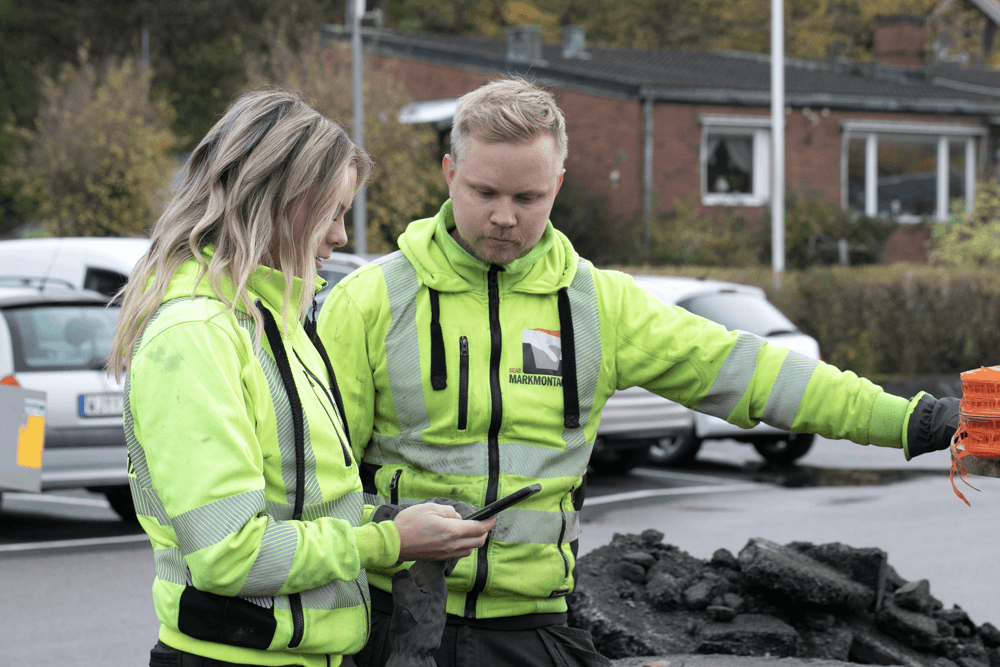 Två medarbetare i varselkläder planerar arbetet vid en byggarbetsplats