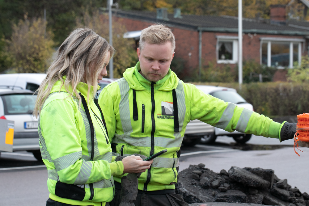 Två medarbetare i varselkläder planerar arbetet vid en byggarbetsplats